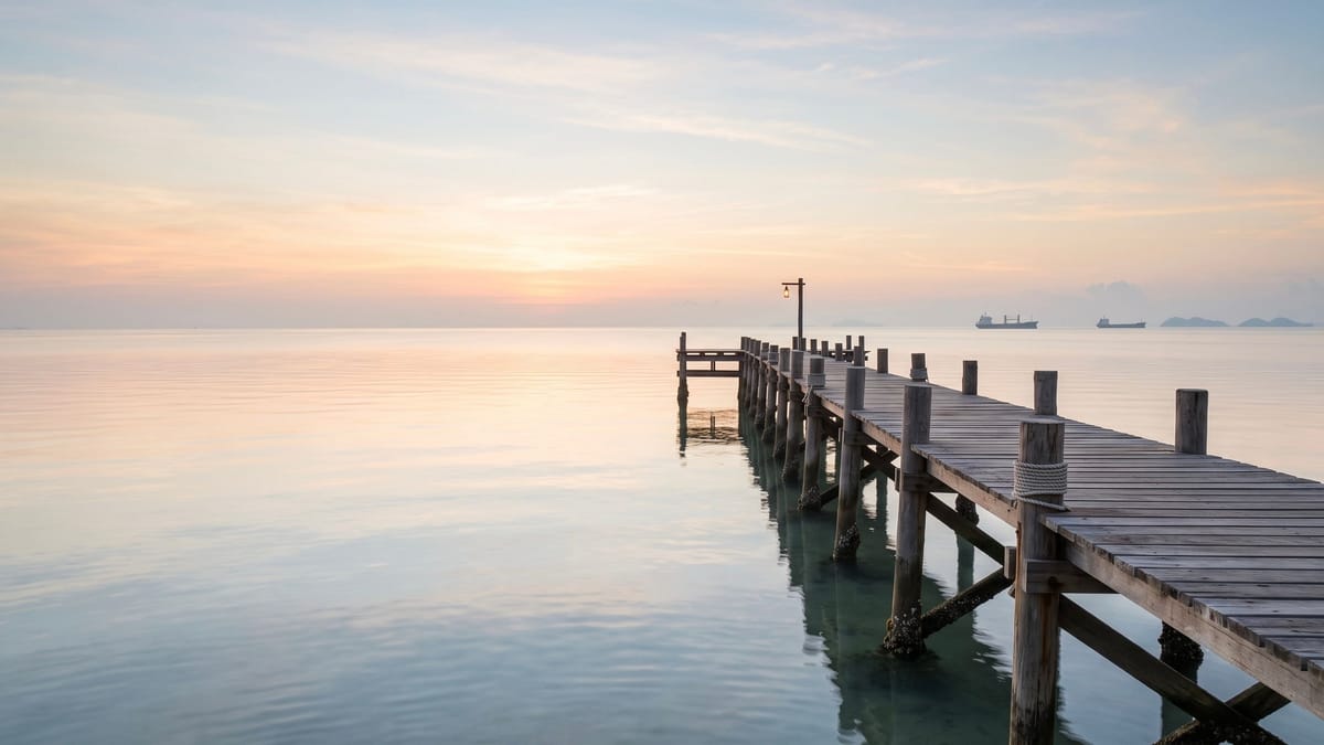 Wooden jetty stretching into a calm sea at dawn