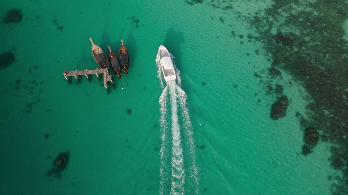 Aerial view of an electric workboat passing moored long-tail fishing boats