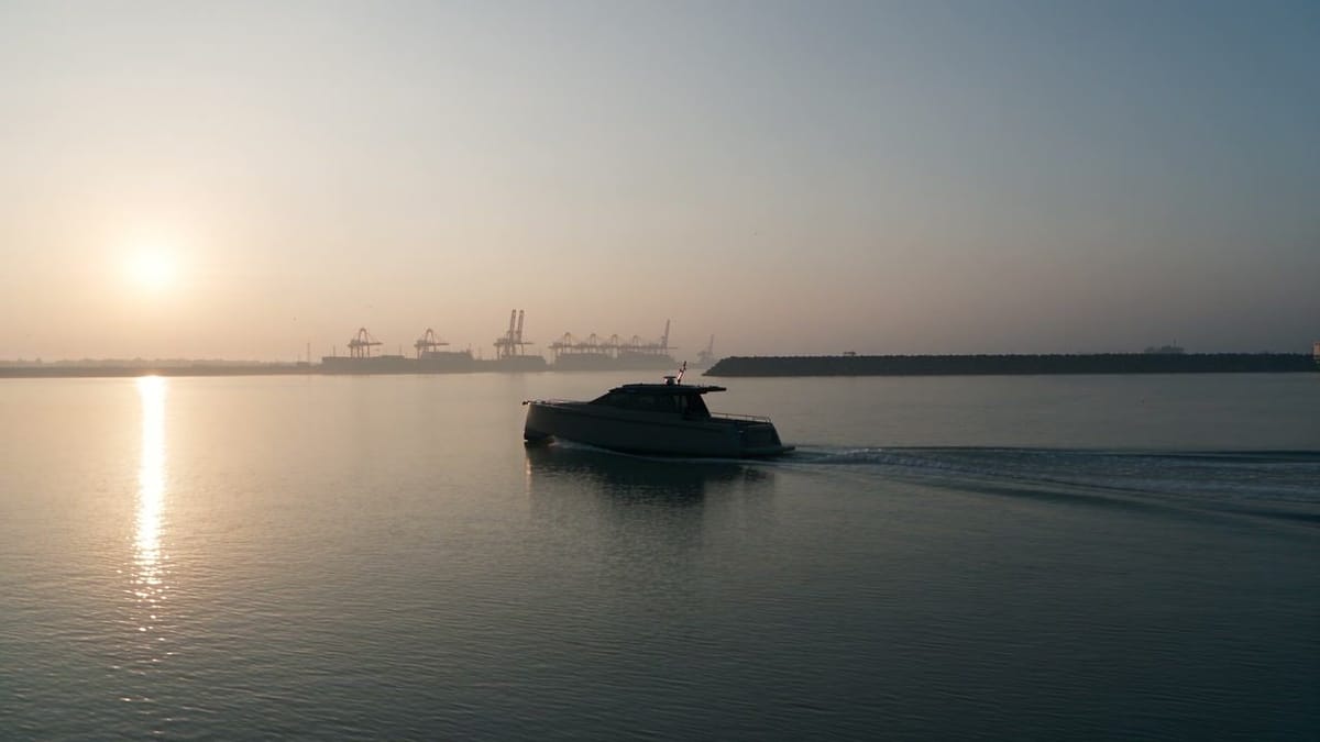 Electric workboat crossing a calm harbour at sunrise